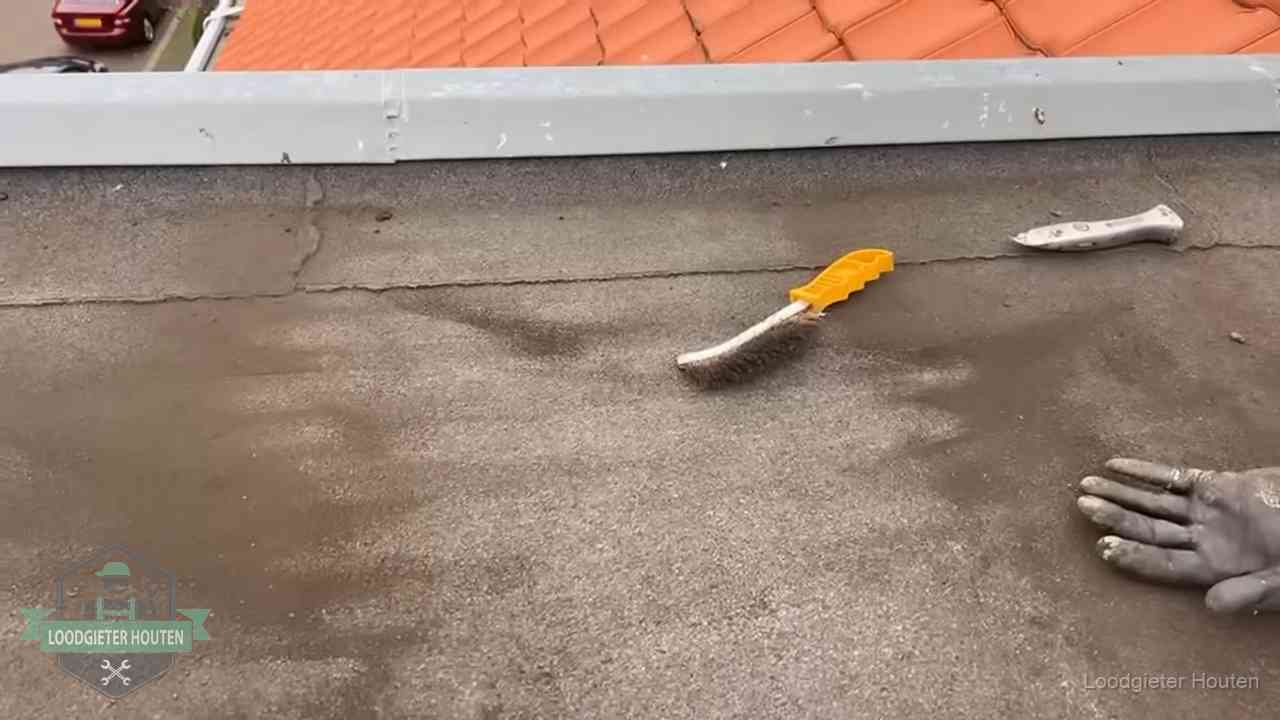 Kosten van daklekkage-reparatie in Houten Dakdekker bereidt een bitumen plat dak voor op reparatie bij de daktrim in Houten