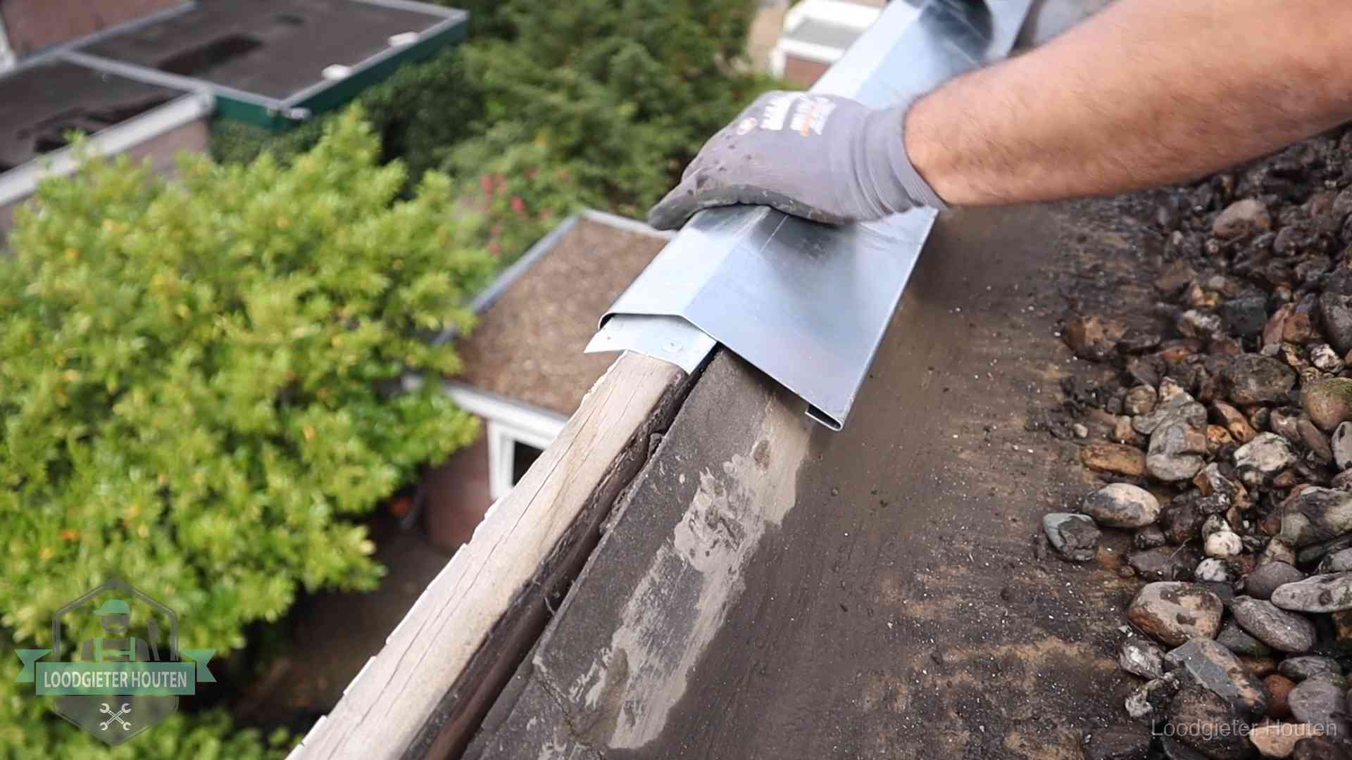 Daklekkage per wijk in Houten Dakdekker plaatst een zinken deklijst op een dakrand met uitzicht over een woonwijk in Houten