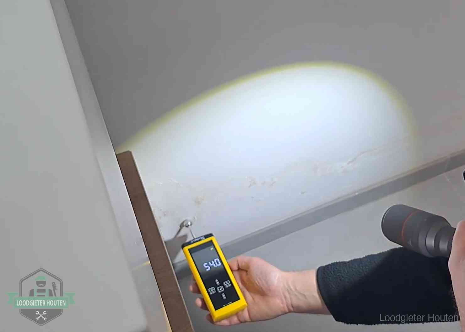 Vochtmeter tegen een natte wand met lekkagesporen in Houten