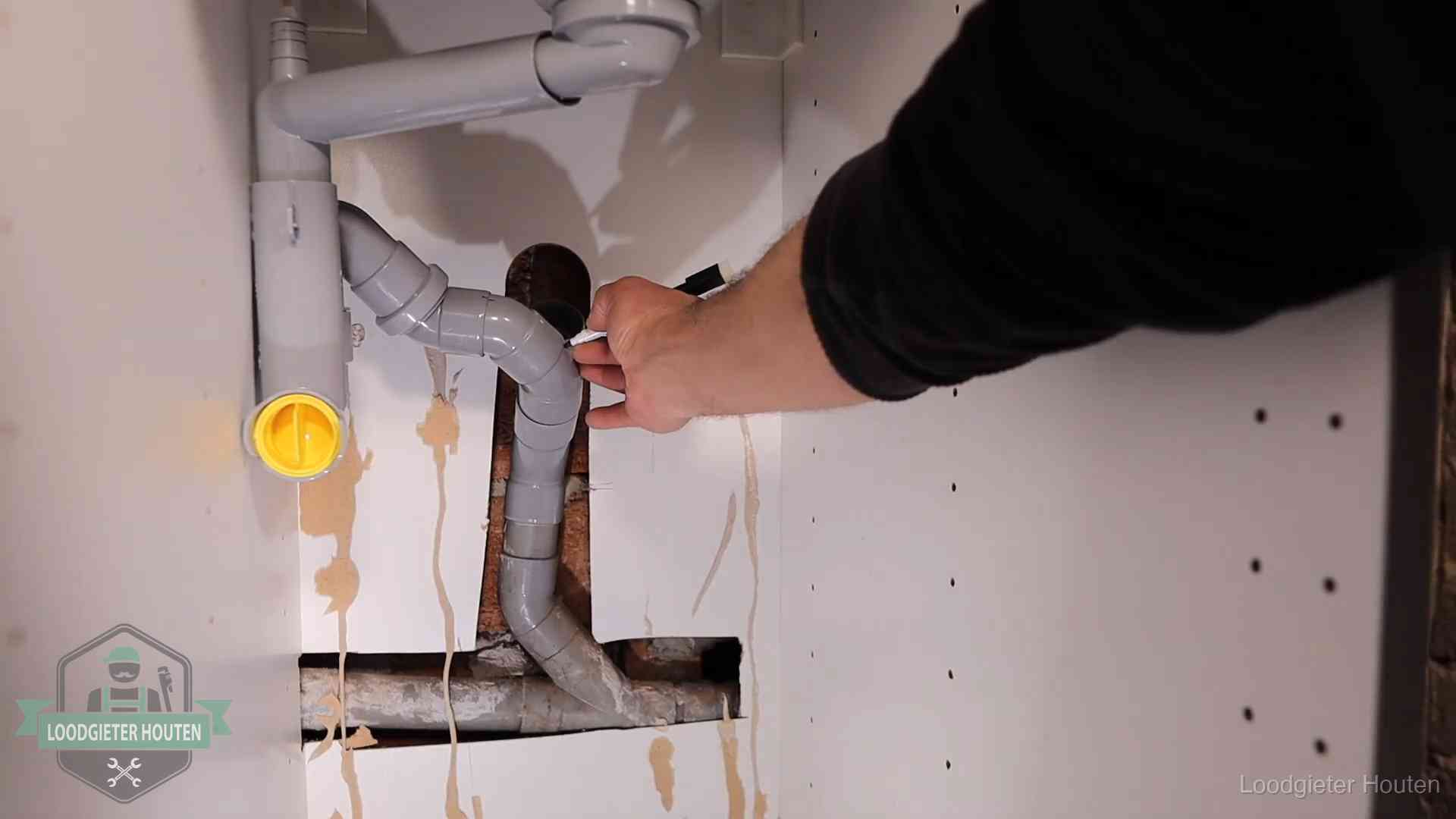 Loodgieter markeert een pvc-afvoerbuis onder een gootsteen in Houten