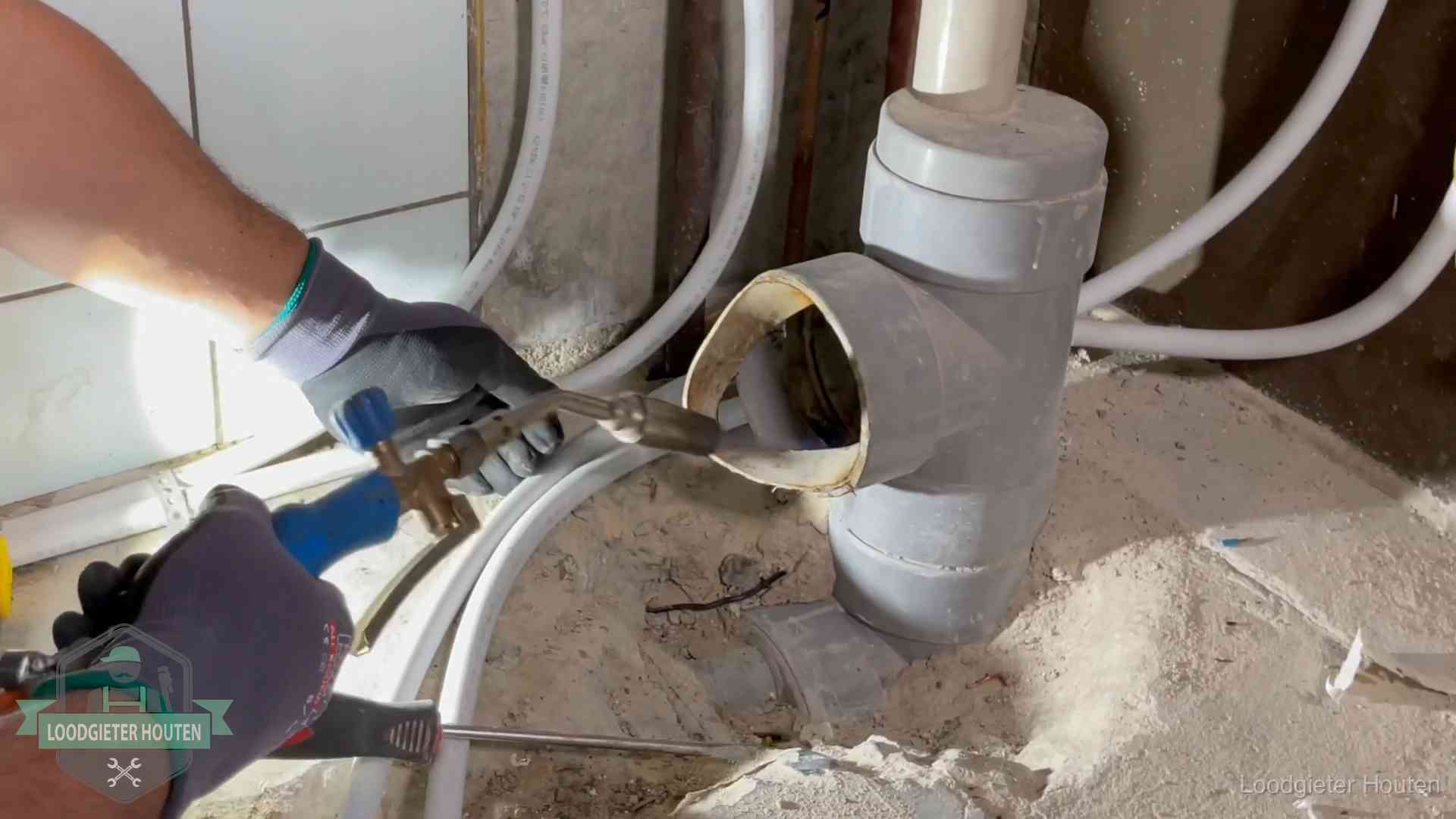Loodgieter werkt met brander en messing kraanwerk aan leidingen in Houten