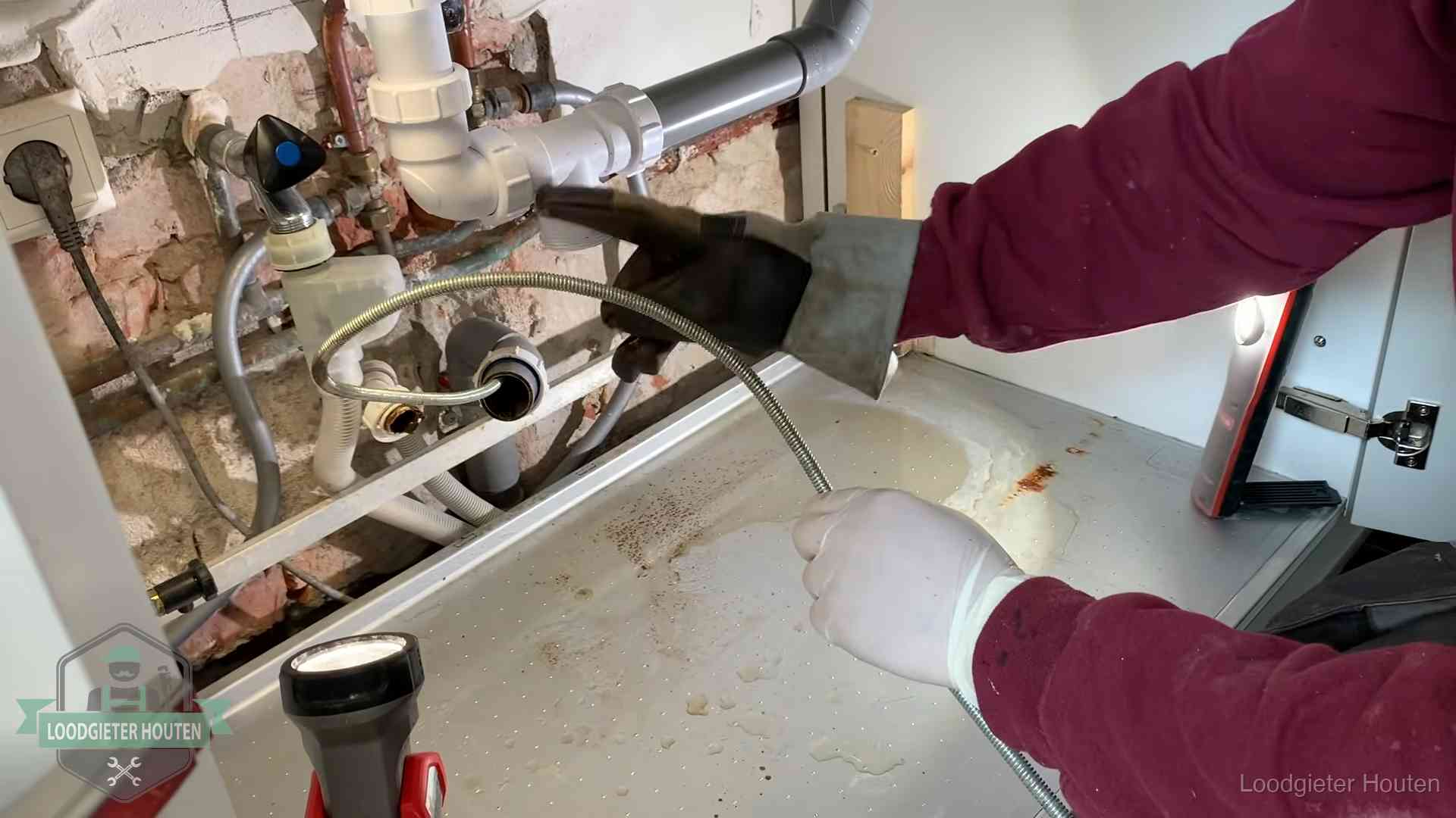 Spiraal of hogedruk in Houten Ontstoppingsveer gaat in een geopende sifonaansluiting onder het aanrecht in Houten