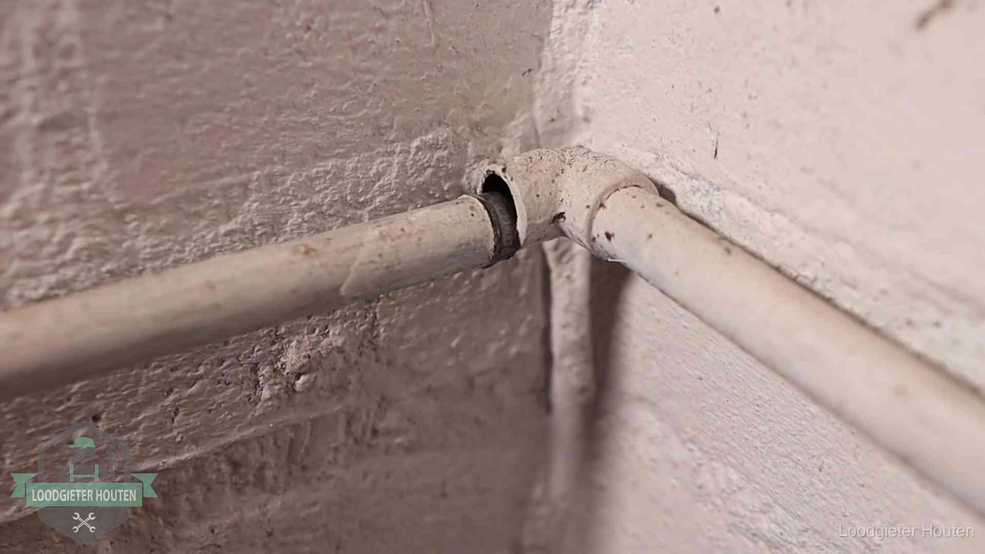 Oude geverfde waterleiding met een losliggende fitting in een woning in Houten
