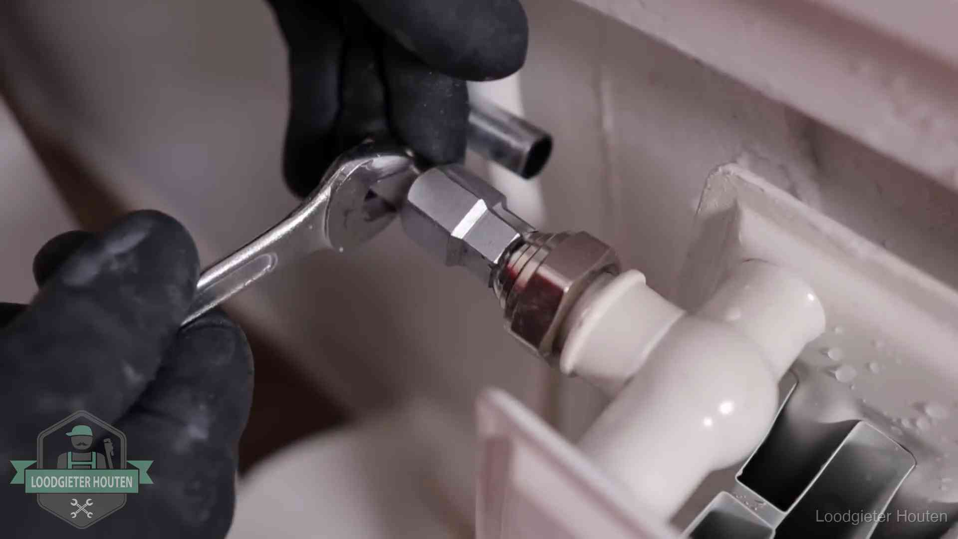 Steeksleutel draait een wartelkoppeling op een radiatorkraan aan in Houten