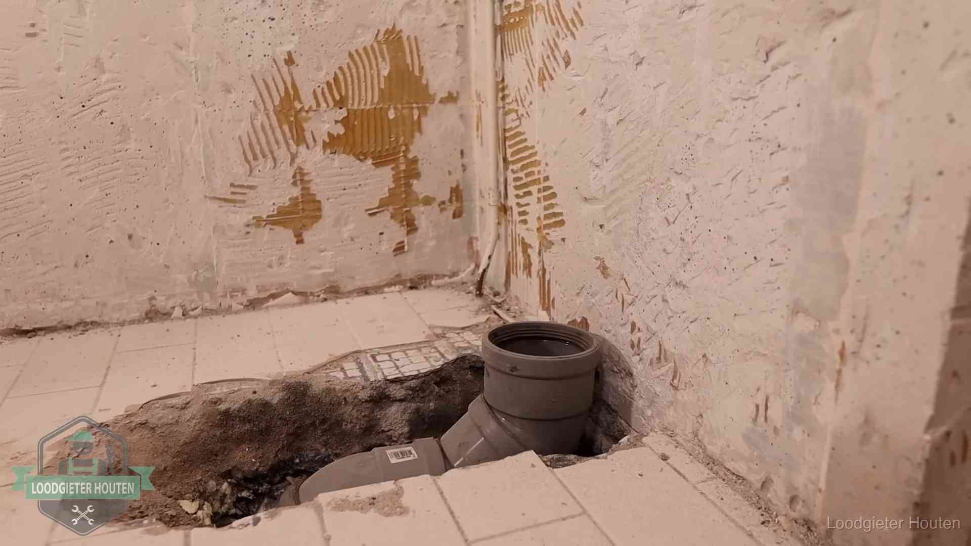 Verzakt riool herstellen in Houten Opengebroken vloer met een nieuwe pvc-rioolbocht in een gegraven sleuf in Houten