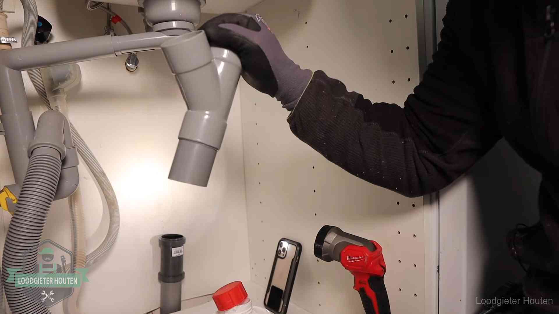 Rioollucht in huis verhelpen in Houten Loodgieter demonteert het sifon- en afvoerwerk onder een gootsteen in Houten bij stankklachten
